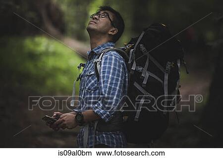 Hiker with backpack and smart phone, looking up View Large Photo Image Picture - Hiker with backpack and smart phone, looking up. Fotosearch
