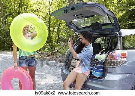 Stock Image - Hikers sitting at rear of car photographing. Fotosearch