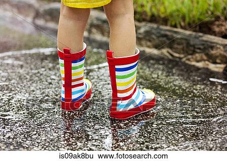 Legs of girl wearing rubber boots standing in rain puddle View Large Photo Image Stock Photograph - Legs of girl wearing rubber boots standing in rain puddle. Fotosearch