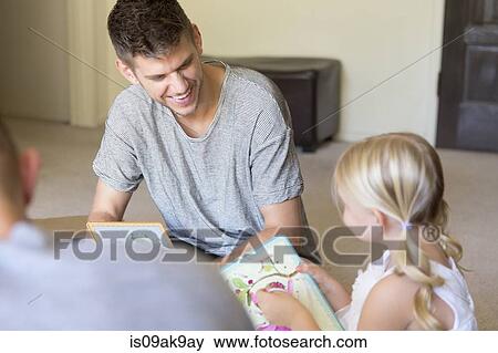 Male couple and daughter threading picture books in sitting room View Large Photo Image Stock Photo - Male couple and daughter threading picture books in sitting room. Fotosearch
