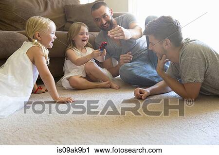 Male couple and two daughters playing on sitting room floor View Large Photo Image Stock Image - Male couple and two daughters playing on sitting room floor. Fotosearch