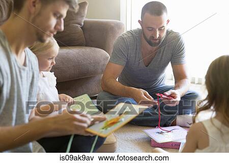 Male couple and two daughters threading picture books on sitting room floor View Large Photo Image Stock Photo - Male couple and two daughters threading picture books on sitting room floor. Fotosearch