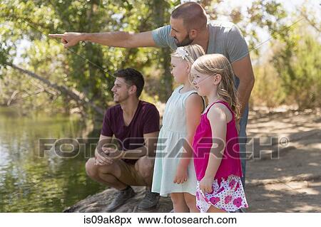 Male couple looking from riverbank with two daughters View Large Photo Image Stock Photo - Male couple looking from riverbank with two daughters. Fotosearch