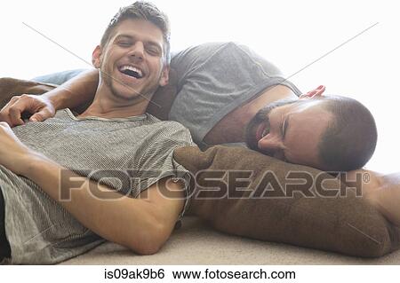 Male couple reclining and laughing on sitting room floor cushions View Large Photo Image Stock Photograph - Male couple reclining and laughing on sitting room floor cushions. Fotosearch