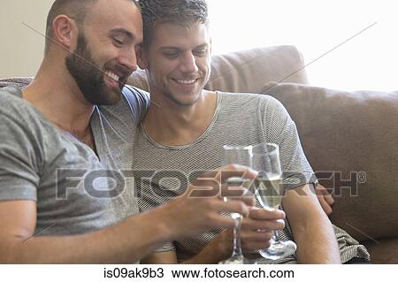Male couple toasting each other with champagne on sitting room sofa View Large Photo Image Stock Image - Male couple toasting each other with champagne on sitting room sofa. Fotosearch