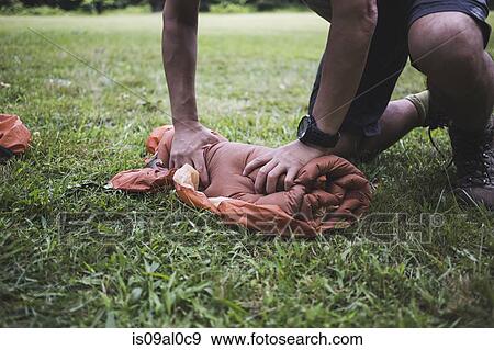 Stock Photo - Man rolling up tent. Fotosearch