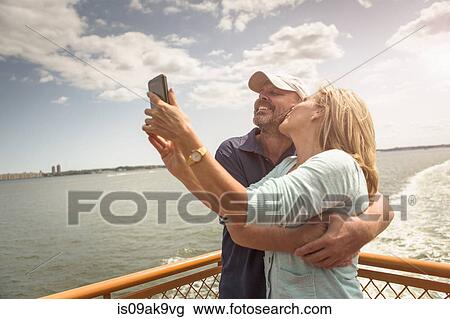 Stock Image - Mature couple photographing themselves on passenger ferry deck. Fotosearch