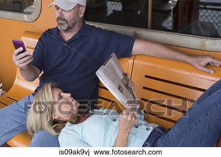 Stock Image - Mature couple sitting on bench on passenger ferry. Fotosearch