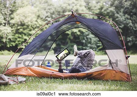 Mature man lying in tent using digital tablet View Large Photo Image Stock Image - Mature man lying in tent using digital tablet. Fotosearch