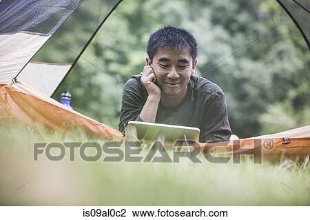 Mature man lying in tent using digital tablet View Large Photo Image Stock Image - Mature man lying in tent using digital tablet. Fotosearch