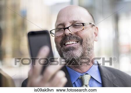 Picture - Mature man using smartphone, close up. Fotosearch