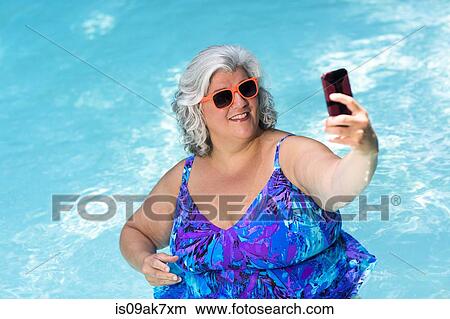Mature woman taking selfie on smartphone at poolside View Large Photo Image Picture - Mature woman taking selfie on smartphone at poolside. Fotosearch