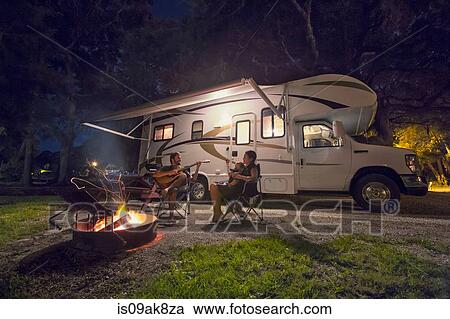 Mid adult couple and baby daughter sitting in front of campfire at night View Large Photo Image Stock Image - Mid adult couple and baby daughter sitting in front of campfire at night. Fotosearch
