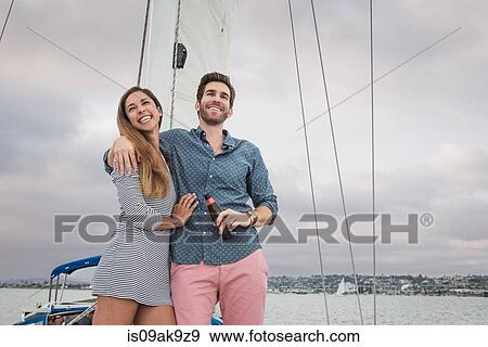 Stock Photo - Mid adult couple on sailing boat, man with arm round woman. Fotosearch