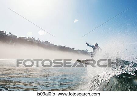 Mid adult male surfer jumping over wave, Leucadia, California, USA View Large Photo Image Picture - Mid adult male surfer jumping over wave, Leucadia, California, USA. Fotosearch