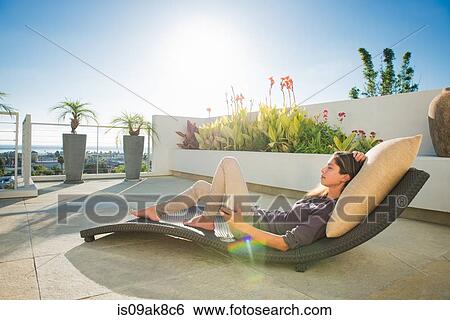 Mid adult woman lying on lounger in penthouse rooftop garden, La Jolla, California, USA View Large Photo Image Stock Photograph - Mid adult woman lying on lounger in penthouse rooftop garden, La Jolla, California, USA. Fotosearch