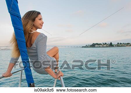 Mid adult woman sitting on railing on sailing boat View Large Photo Image Stock Photograph - Mid adult woman sitting on railing on sailing boat. Fotosearch