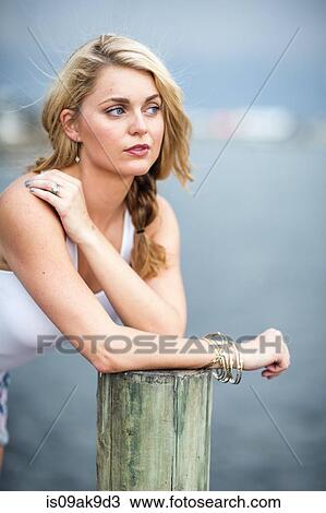 Portrait of a young woman leaning on post View Large Photo Image Stock Image - Portrait of a young woman leaning on post. Fotosearch