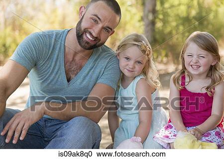 Portrait of father and two daughters in park View Large Photo Image Stock Image - Portrait of father and two daughters in park. Fotosearch