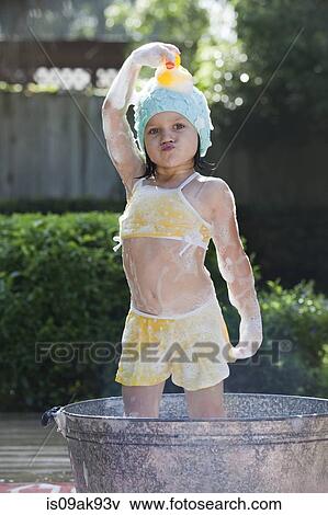Portrait of girl standing in bubble bath in garden holding rubber duck on head View Large Photo Image Stock Photo - Portrait of girl standing in bubble bath in garden holding rubber duck on head. Fotosearch