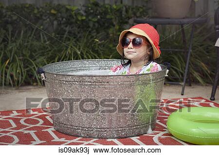 Portrait of girl wearing sunhat and sunglasses sitting in bubble bath in garden View Large Photo Image Stock Image - Portrait of girl wearing sunhat and sunglasses sitting in bubble bath in garden. Fotosearch