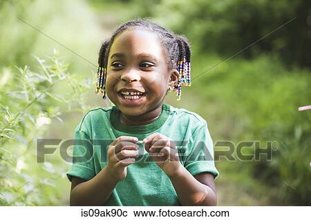 Stock Image - Portrait of girl with plant in parkland eco camp. Fotosearch