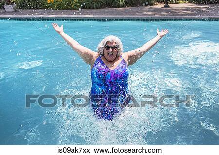 Stock Photo - Portrait of mature woman splashing about in swimming pool. Fotosearch