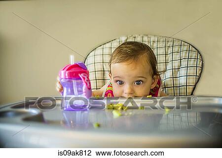 Stock Image - Portrait of shy baby girl in high chair. Fotosearch