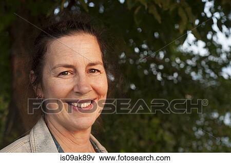 Portrait of smiling mature woman in woodland View Large Photo Image Stock Photo - Portrait of smiling mature woman in woodland. Fotosearch