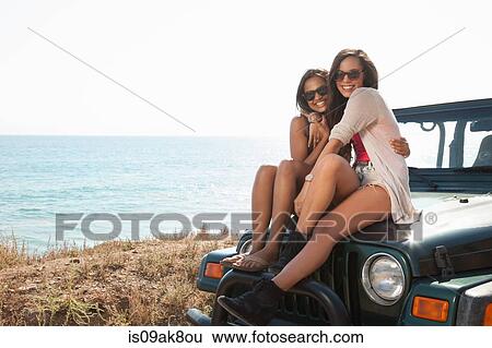 Portrait of two young women sitting on jeep hood at coast, Malibu, California, USA View Large Photo Image Stock Photograph - Portrait of two young women sitting on jeep hood at coast, Malibu, California, USA. Fotosearch