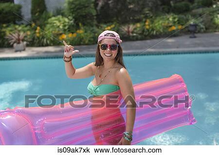Portrait of young woman making hang loose sign at poolside View Large Photo Image Stock Image - Portrait of young woman making hang loose sign at poolside. Fotosearch