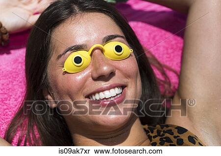 Stock Photography - Portrait of young woman sunbathing, wearing goggles. Fotosearch