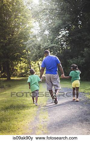 Rear view of father holding hands with son and daughter at parkland eco camp View Large Photo Image Stock Photo - Rear view of father holding hands with son and daughter at parkland eco camp. Fotosearch