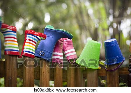 Row of rubber boots and buckets on top of garden fence View Large Photo Image Stock Photo - Row of rubber boots and buckets on top of garden fence. Fotosearch