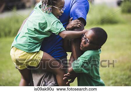Son and daughter play fighting father at parkland eco camp View Large Photo Image Stock Photograph - Son and daughter play fighting father at parkland eco camp. Fotosearch