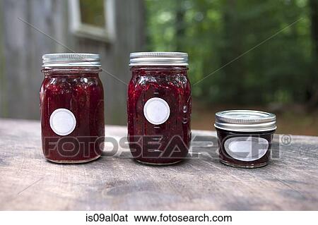 Stock Photograph - Three jars of jam on garden table. Fotosearch