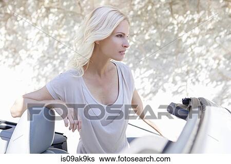 Woman beside her convertible car View Large Photo Image Stock Photograph - Woman beside her convertible car. Fotosearch