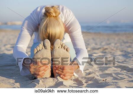 Stock Image - Woman doing yoga prayer stretch on the beach. Fotosearch