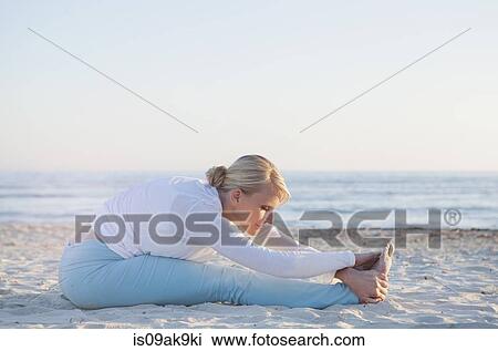 Stock Image - Woman doing yoga prayer stretch on the beach. Fotosearch