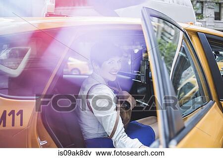 Stock Photo - Woman getting into yellow taxi, New York, US. Fotosearch