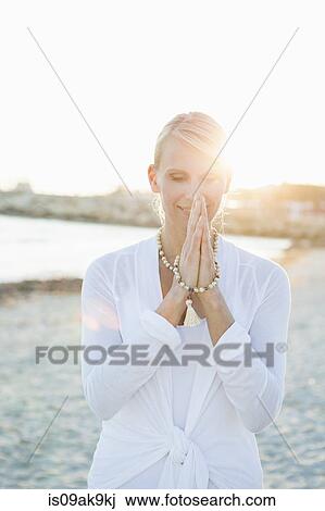 Stock Image - Woman in yoga prayer pose on the beach. Fotosearch