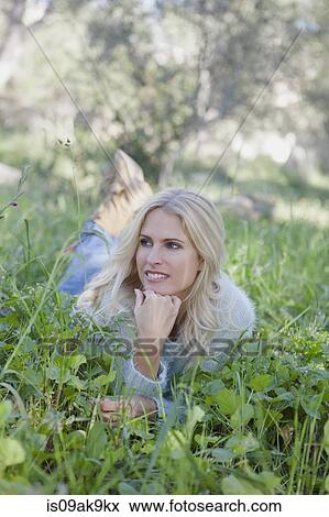 Stock Photo - Woman lying on grass in garden. Fotosearch