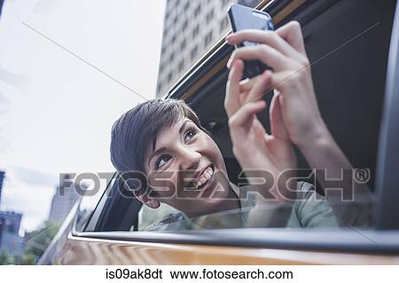 Woman photographing from yellow taxi, New York, US View Large Photo Image Stock Photograph - Woman photographing from yellow taxi, New York, US. Fotosearch