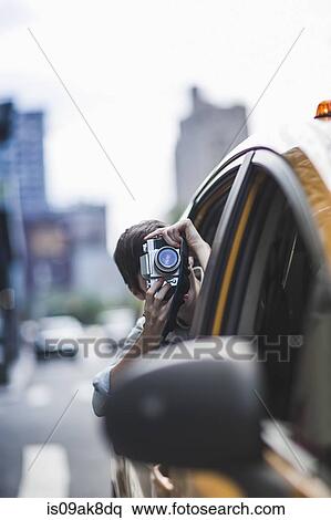 Stock Photography - Woman photographing from yellow taxi, New York, US. Fotosearch