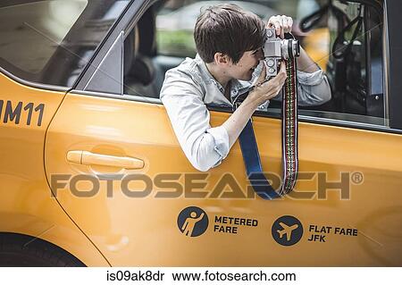 Woman photographing from yellow taxi, New York, US View Large Photo Image Stock Photography - Woman photographing from yellow taxi, New York, US. Fotosearch