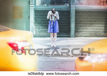 Stock Photography - Woman photographing on street, New York, US. Fotosearch