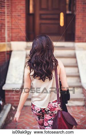 Stock Photo - Woman walking towards stairs to front door. Fotosearch