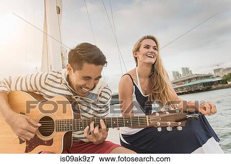 Young couple on sailing boat, man playing guitar View Large Photo Image Stock Photo - Young couple on sailing boat, man playing guitar. Fotosearch