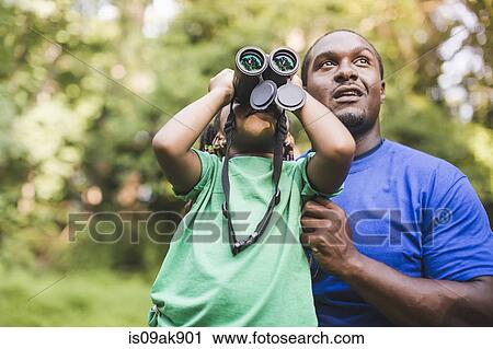 Stock Image - Young father and daughter bird watching in eco forest camp. Fotosearch