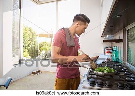 Young man following cooking instructions in kitchen View Large Photo Image Stock Image - Young man following cooking instructions in kitchen. Fotosearch